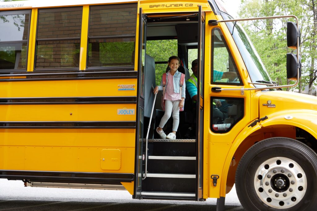 A girl getting off an electric school bus.