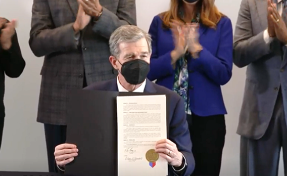 Governor Cooper displays Executive Order 246 at a signing ceremony.