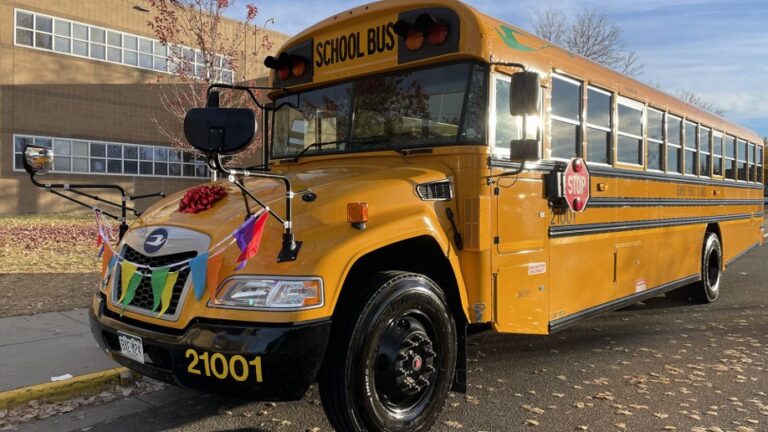 An electric school bus in front of a school in Denver.