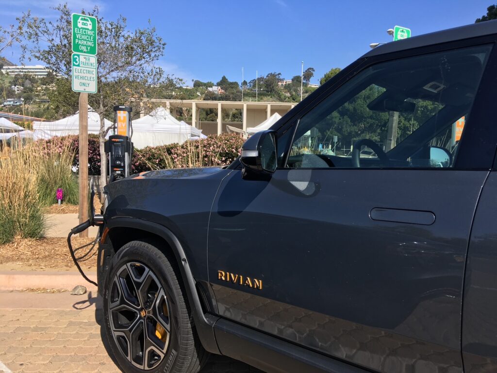 A Rivian electric pickup charging at a public charging station.